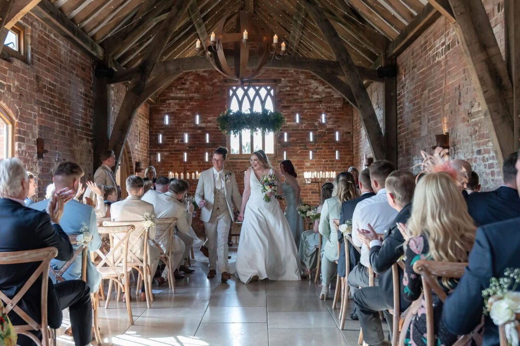 Couple walk down the aisle joyfully.