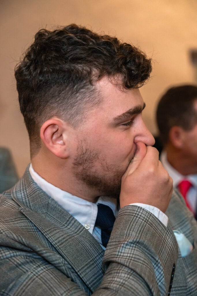Man in plaid suit holding nose at event