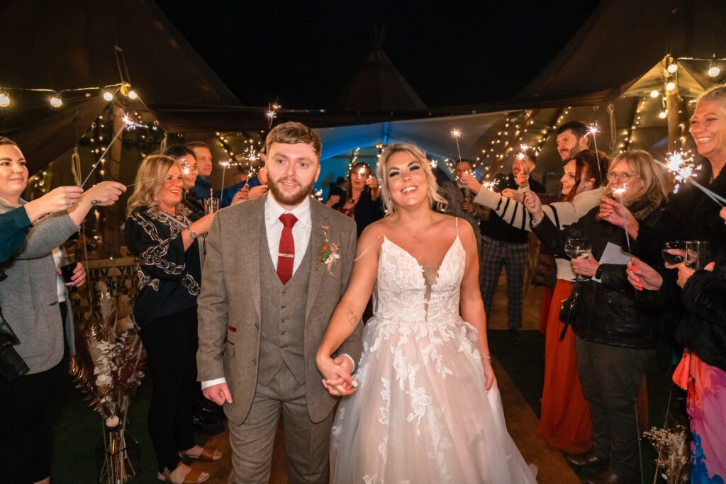 Bride and groom with sparklers at wedding celebration.