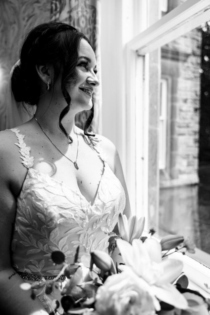 Bride smiling by window holding bouquet