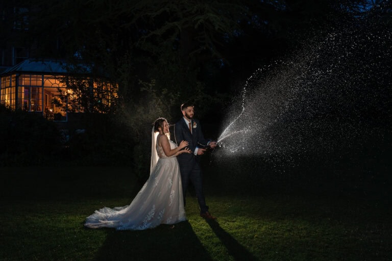 Bride and groom celebrate with champagne outdoors.