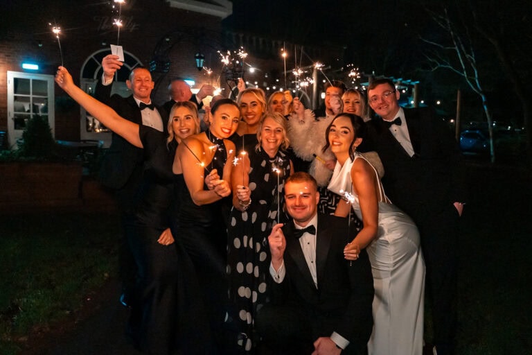 Group holding sparklers at nighttime formal celebration